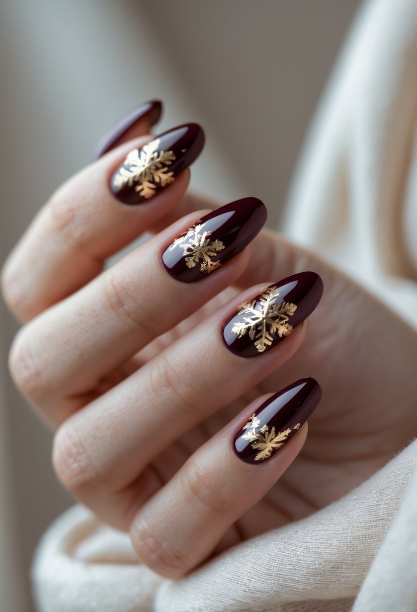 Close-up of a hand with deep burgundy nails decorated with gold foil accents.